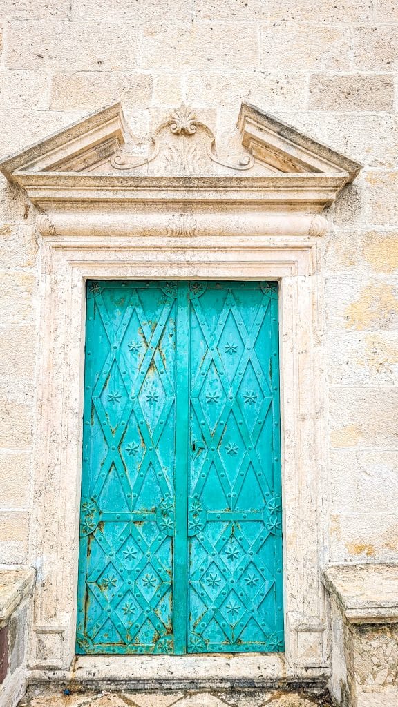 Turquoise old metal door somewhere in the old town of Kotor. A complete travel guide to Dubrovnik: city walls, fortresses, and day trips