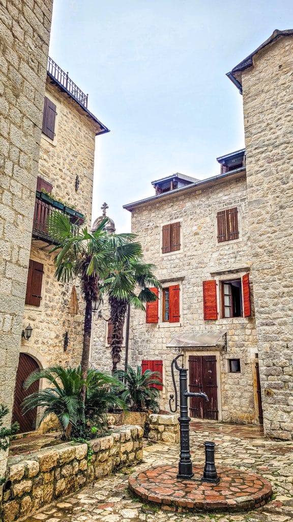 Medieval architecture, palm trees and old water pump in Kotor. A complete travel guide to Dubrovnik: city walls, fortresses, and day trips