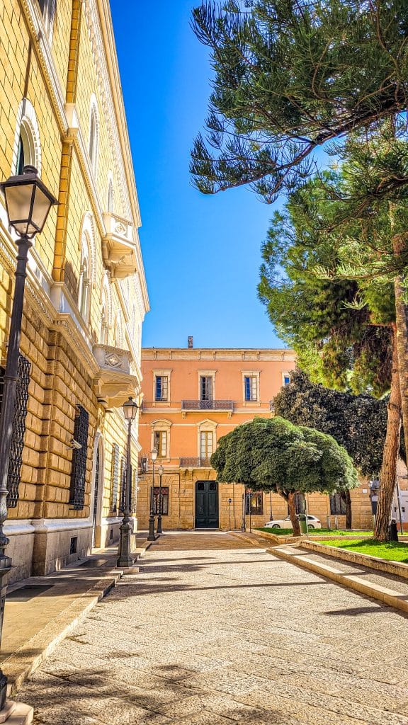 Salmon pink coloured building and trees at Piazzetta Santa Chiara. Why Lecce Is Southern Italy's Most Underrated Travel Destination